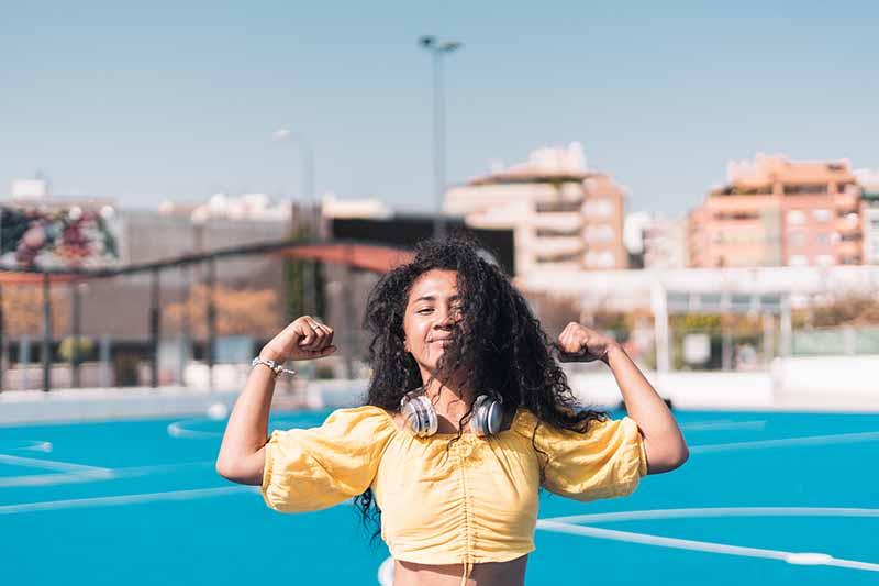 Young  African American girl smiling in yellow T-shirt raising her arms